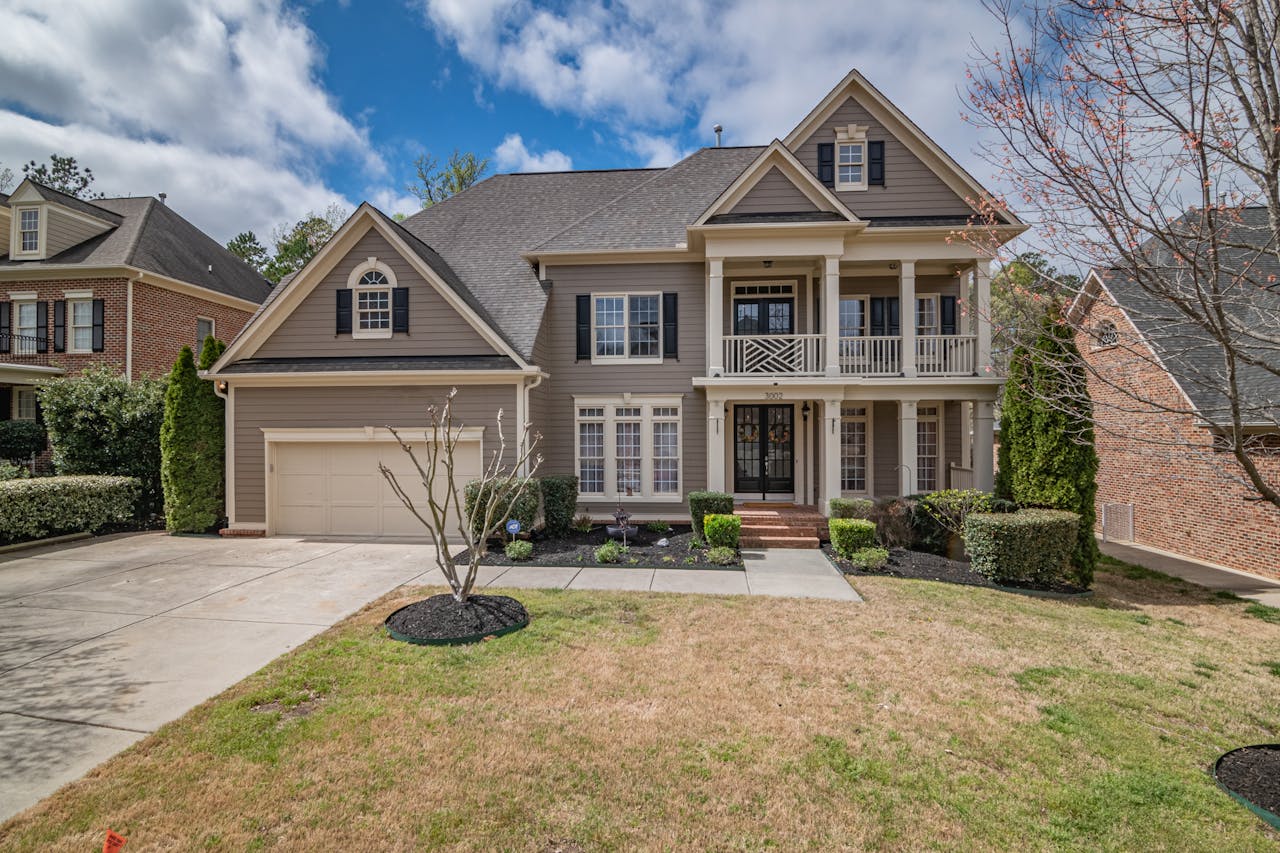 A beautiful two-story suburban house with a well-maintained lawn and elegant facade, showcasing classic architectural design.